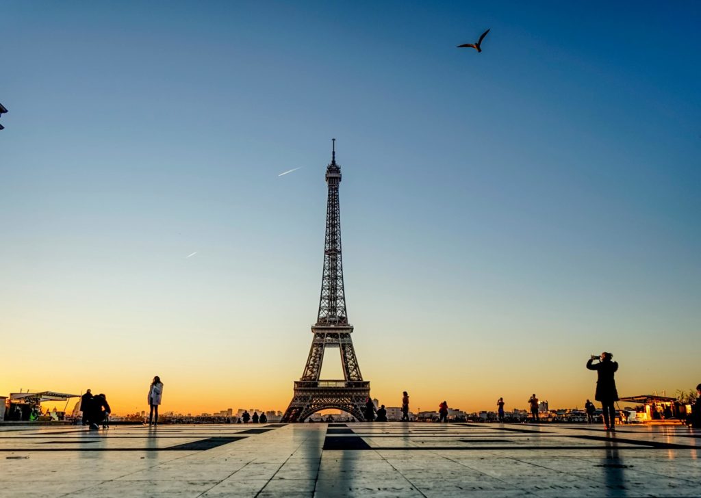 Capture of the Eiffel Tower at sunrise with silhouettes of people and birds in Paris, France.